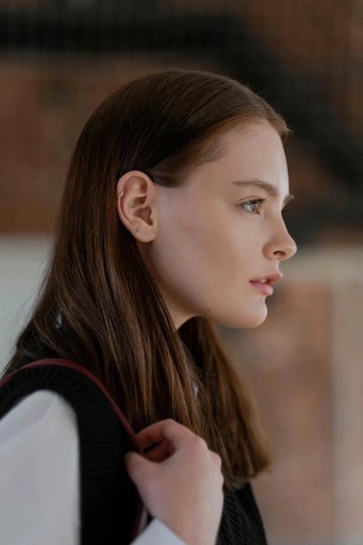 a woman in a white shirt and black vest, inspired by Emma Andijewska, trending on pexels, profile view, mackenzie foy, left ear, natali portman