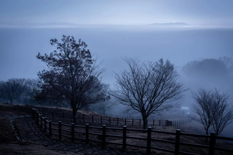 a fence and some trees on a hill, inspired by Kaii Higashiyama, pexels contest winner, blue fog, fog mads berg, in karuizawa, portrait photo