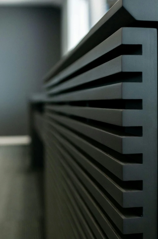 a black radiator sitting on top of a wooden floor, inspired by Pierre Soulages, unsplash, close up shot from the side, modular, vantablack wall, features intricate detail