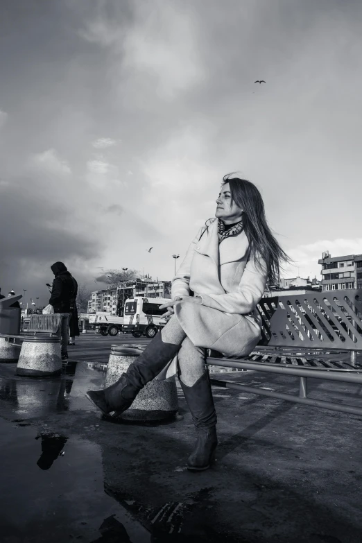 a black and white photo of a woman sitting on a bench, wearing boots, istanbul, skies behind, nepal