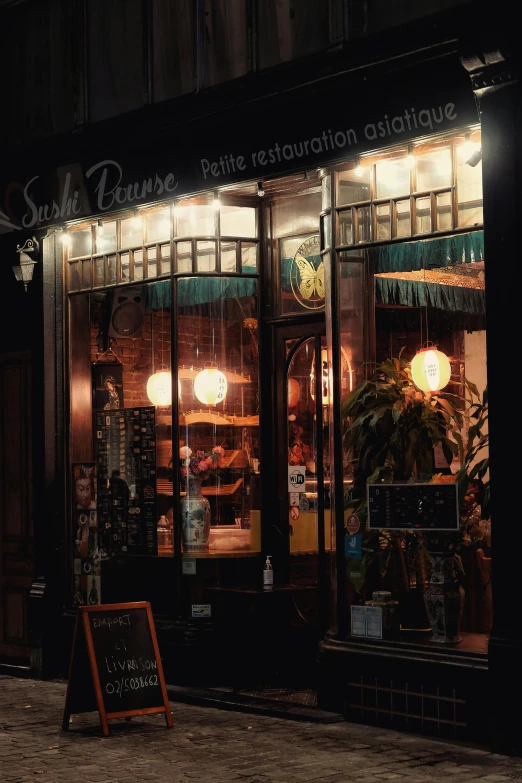 a store front on a city street at night, a photo, unsplash, art nouveau, japanese fusion cuisine, in paris, sunraise, 2 0 0 0's photo