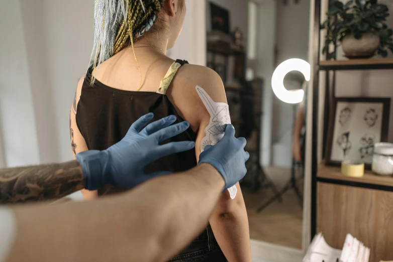 a woman getting a tattoo on her arm, trending on pexels, hyperrealism, covered in bandages, over his shoulder, behind the scenes photo, thumbnail