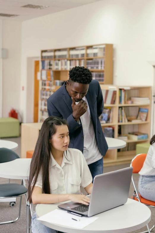 a group of people sitting around a table with a laptop, by Jang Seung-eop, trending on pexels, paris school, standing in class, black man, in a library, intense flirting