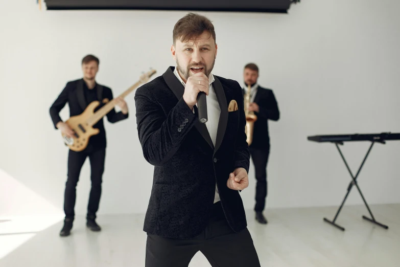 a man in a suit singing into a microphone, an album cover, inspired by János Donát, trending on pixabay, in a white room, ukrainian, band playing, striking a pose