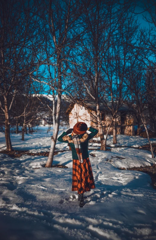 a woman standing in the snow with her hands on her head, a picture, inspired by Elsa Bleda, pexels contest winner, visual art, patterned clothing, in a village, iphone photo, russian clothes