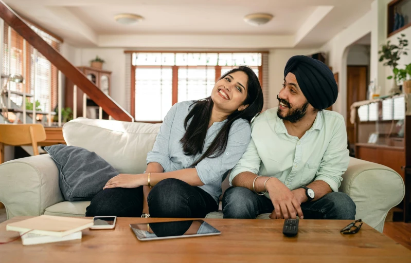 a man and a woman sitting on a couch, inspired by Manjit Bawa, pexels, happening, watching tv, promotional image, smiling couple, looking across the shoulder