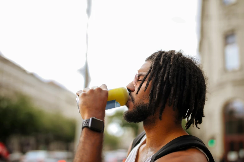 a man with dreadlocks drinking from a cup, pexels contest winner, wearing yellow croptop, wearing fitness gear, profile image, street photo