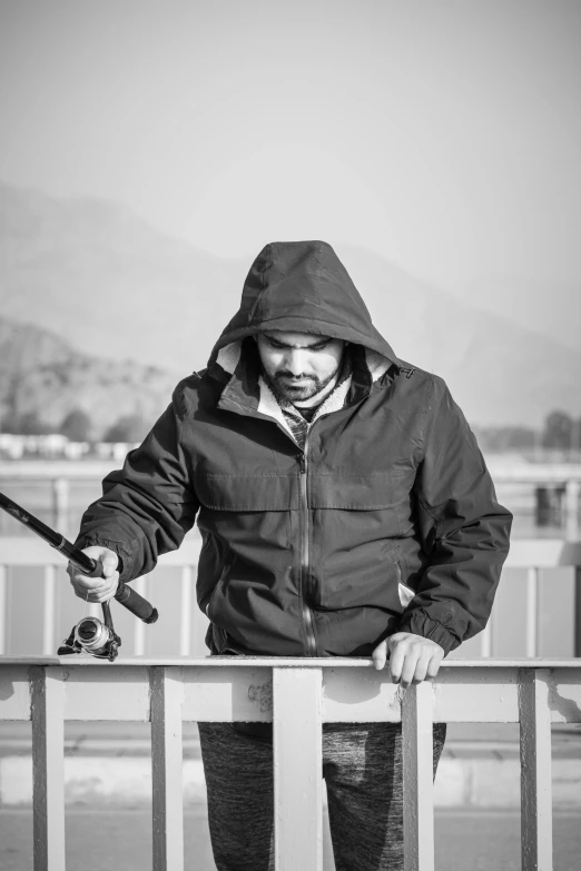 a black and white photo of a man holding a fishing rod, a black and white photo, pexels contest winner, an afghan male type, chilly, mechanics, colour corrected