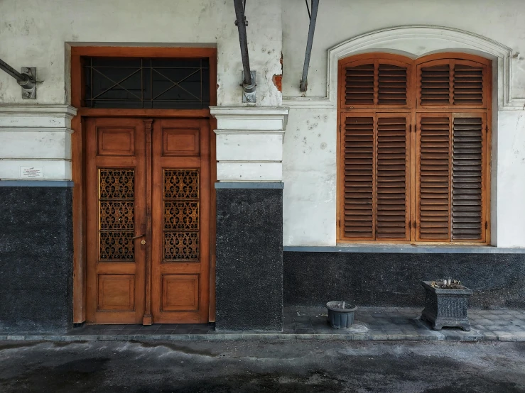 a man sitting on a bench in front of a building, by Basuki Abdullah, pexels contest winner, hyperrealism, wood door, dark grey and orange colours, 1910s architecture, laquer and steel