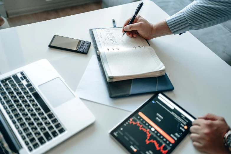 a couple of people sitting at a table with laptops, trending on pexels, analytical art, pen and paper, numerical, thumbnail, graphs