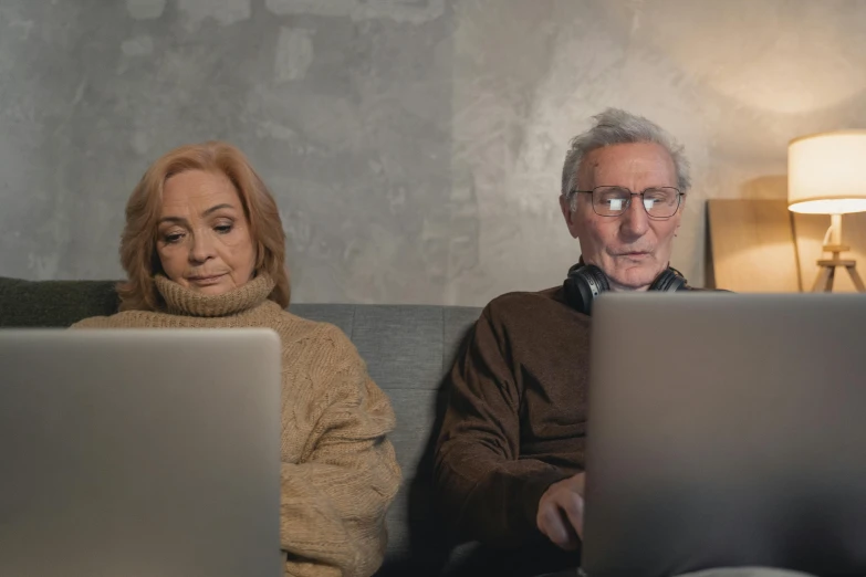 a man and a woman sitting on a couch with laptops, pexels, two old people, brown, avatar image, cinematic image