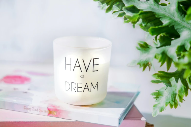 a candle sitting on top of a stack of books, by Elaine Hamilton, unsplash, graffiti, you may say i'm a dreamer, white holographic plastic, modern studio light soft colour, ! dream