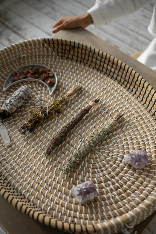 a wicker basket sitting on top of a wooden table, organic crystals, glass and gold pipes, salvia, displayed