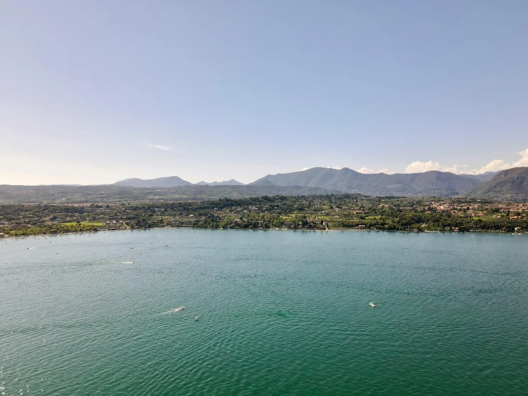 a large body of water with mountains in the background, by Niko Henrichon, pexels contest winner, les nabis, aerial footage, photo of zurich, clear blue skies, orazio gentileschi style