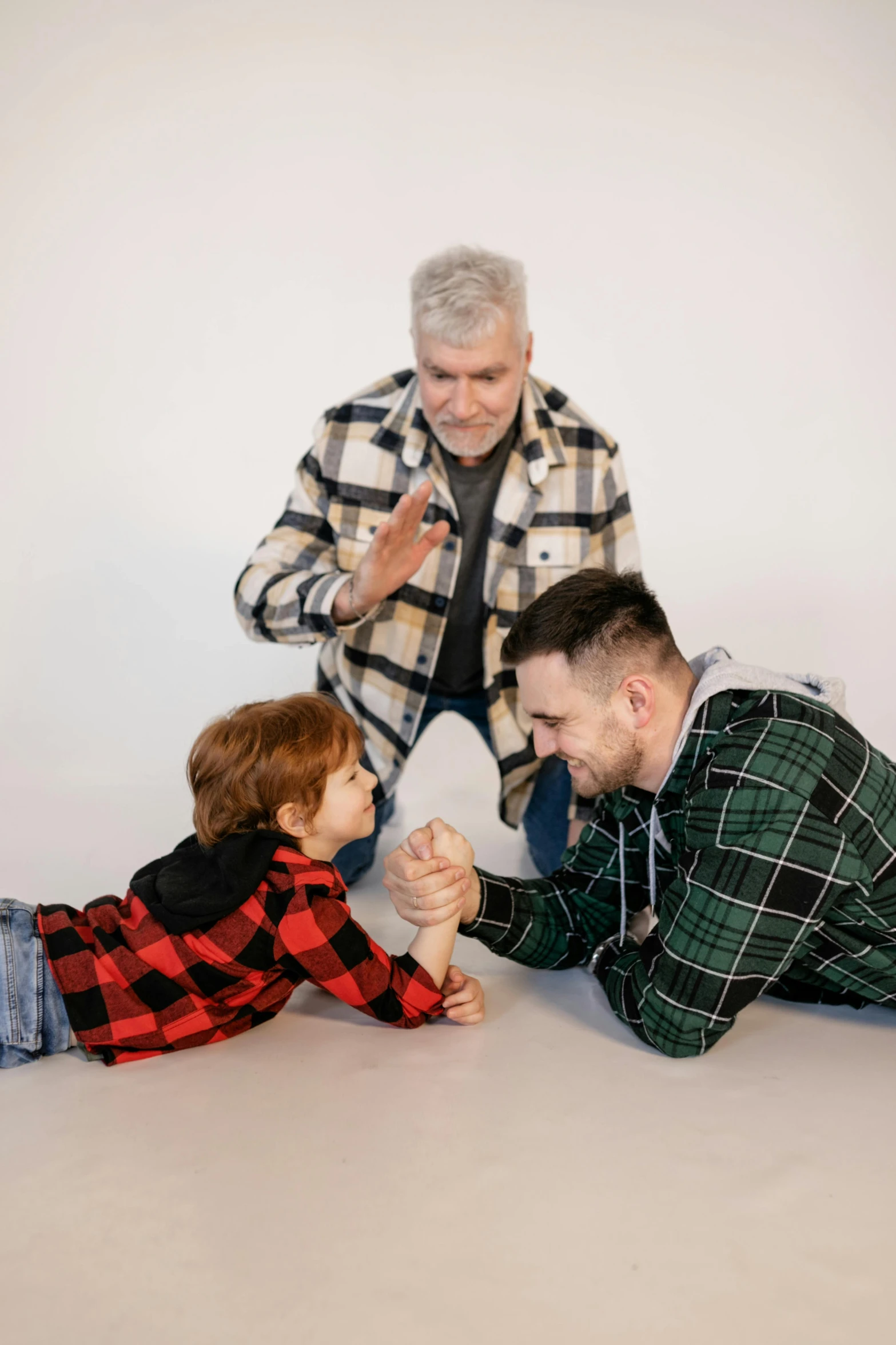 a man sitting on the floor next to a little boy, a colorized photo, pexels contest winner, dau-al-set, gray haired, large fists, wearing a plaid shirt, holding hands