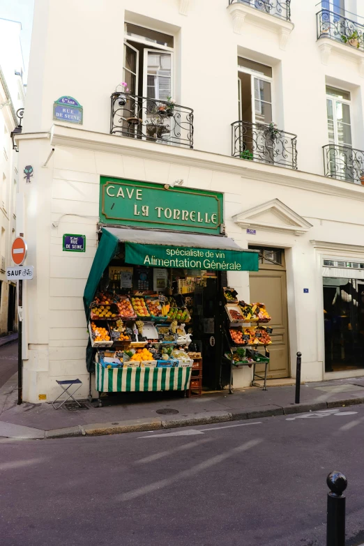 a white building with a green awning in front of it, inspired by Maurice Utrillo, art nouveau, wine cellar full of food, les catacombes, exiting store, yellow aureole