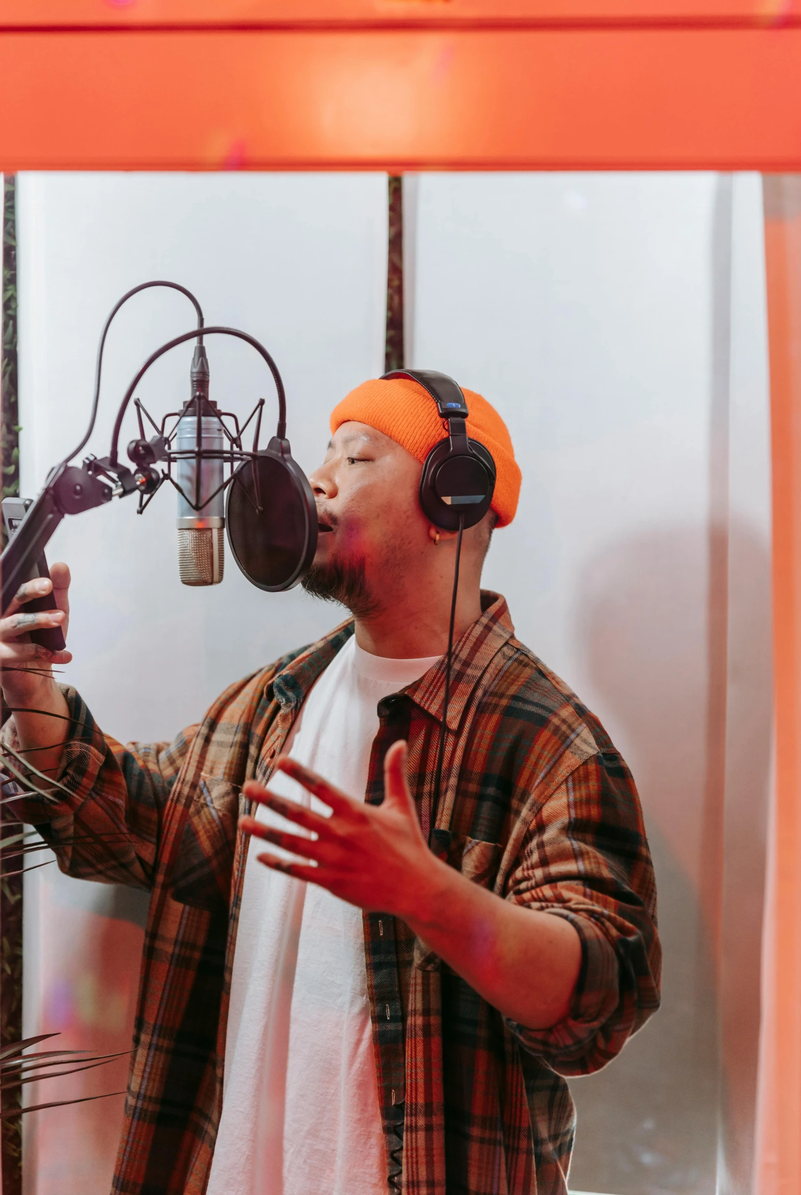 a man that is standing in front of a microphone, an album cover, trending on pexels, asian male, studio orange, rapping into microphone, unfinished