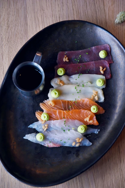 a close up of a plate of food on a table, mingei, jewel fishes, flatlay, black, deep colour