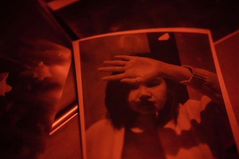 a man taking a picture of himself in a mirror, pexels contest winner, visual art, lit from below with red lighting, a young asian woman, orange tint, hands shielding face