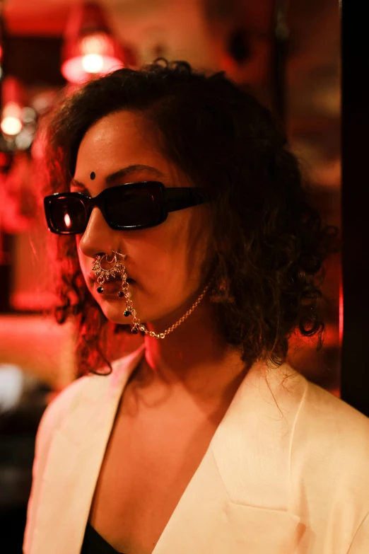 a woman with a piercing on her nose, an album cover, inspired by Nan Goldin, unsplash, renaissance, provocative indian, sunglasses, nightlife, intricate chrome chains