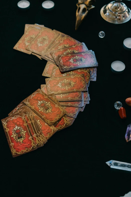 a bunch of cards sitting on top of a table, renaissance, red brocade and blue gemstones, mana flowing around it, wide overhead shot, apothecary
