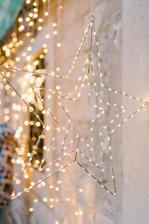 a lighted star hanging from the side of a building, a picture, trending on pexels, light and space, gold decorations, pastel lighting, fully decorated, bright thin wires