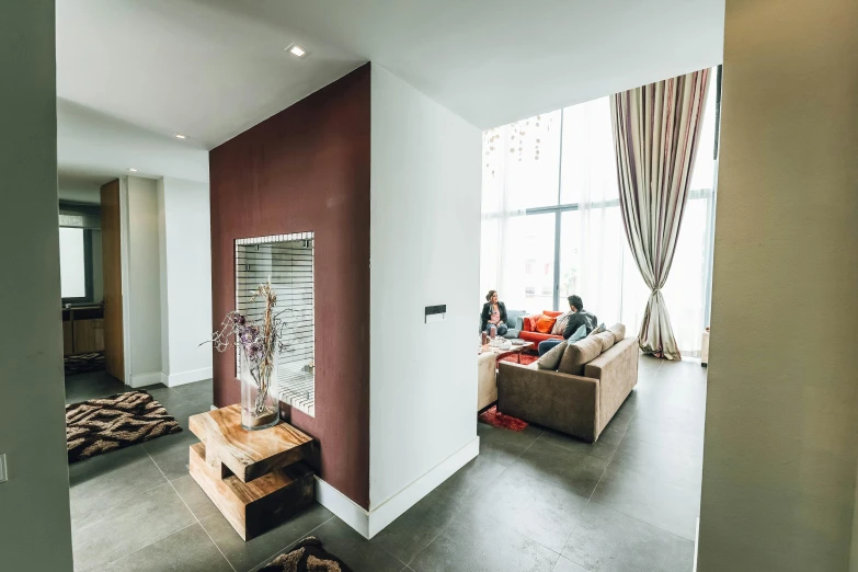 a couple of people sitting on a couch in a living room, by Jan Tengnagel, unsplash, maroon accents, apartment hallway, penthouse, bright daylight indoor photo
