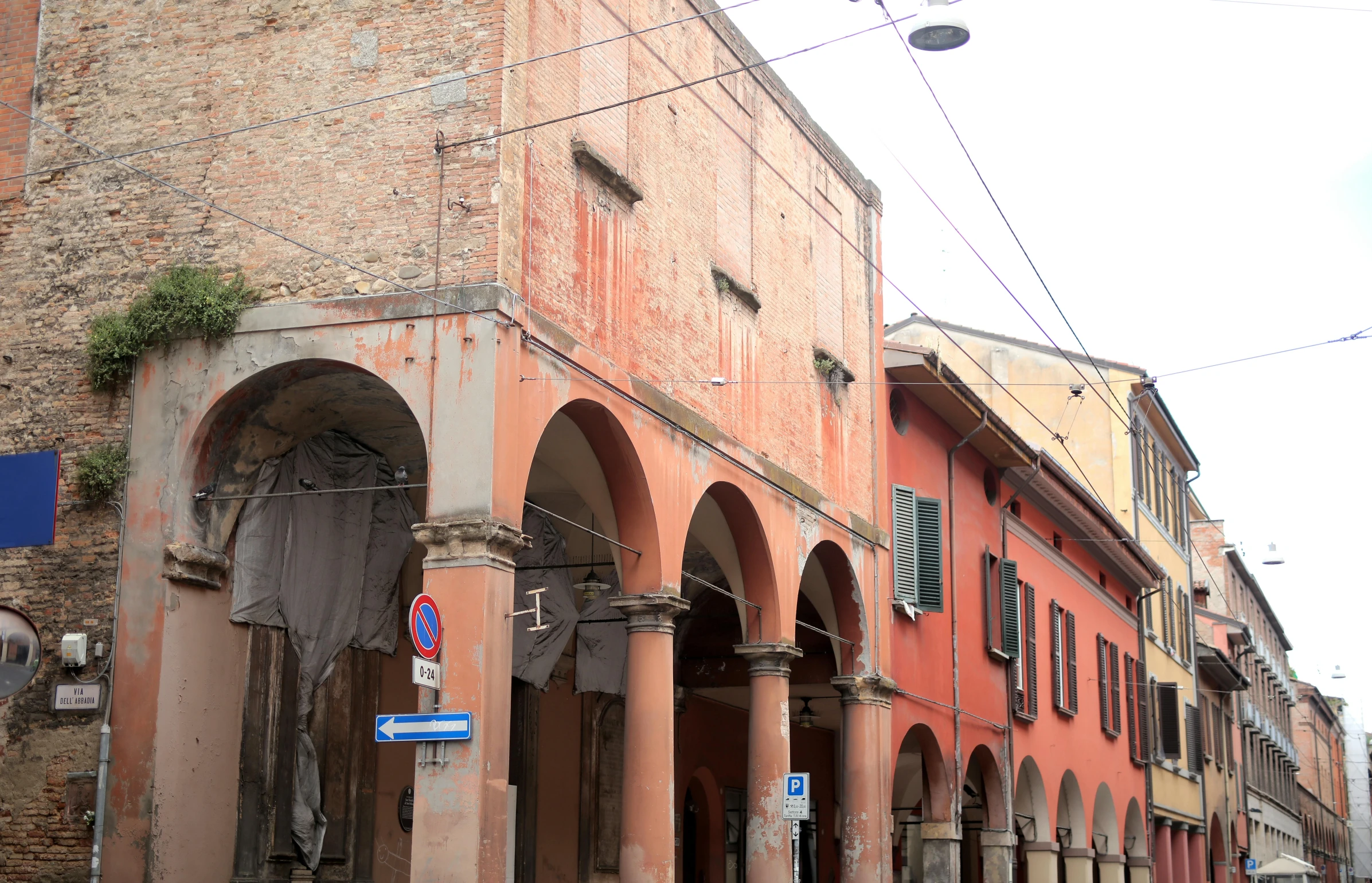 a group of people walking down a street next to tall buildings, an album cover, inspired by Niccolò dell' Abbate, pexels contest winner, renaissance, old abandoned building, high arched ceiling, red bricks, brown