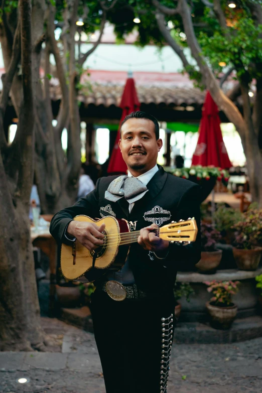 a man in a sombren playing a guitar, an album cover, inspired by Germán Londoño, pexels contest winner, happening, standing in a cantina, ornately dressed, patio, headshot photo