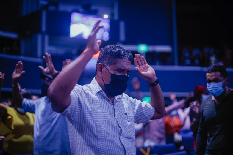 a man wearing a face mask standing in front of a crowd, pexels contest winner, happening, prayer hands, avatar image, in church, sri lanka