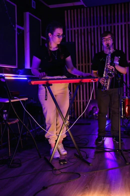 a group of people playing musical instruments in a room, purple bridges with leggins, keyboardist, charli bowater, uncropped