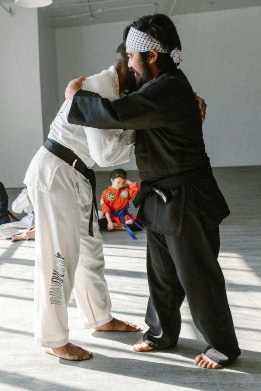 a couple of men standing next to each other in a room, a picture, by Nina Hamnett, unsplash, happening, doing martial arts, hugging her knees, performance, kids