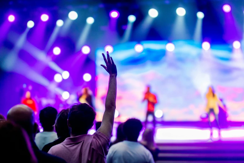 a group of people standing on top of a stage, pexels, happening, church background!, blue and purple lighting, people enjoying the show, holding a holy symbol