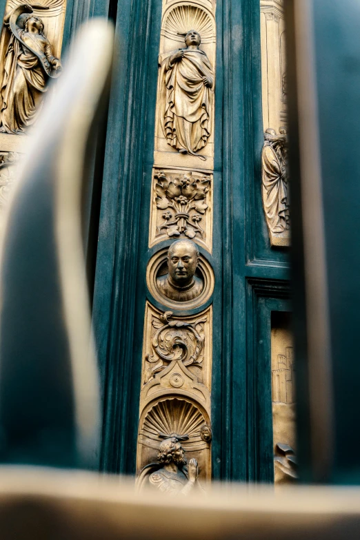 a close up of the front door of a building, an album cover, pexels contest winner, baroque, gold and green, details faces, architecture carved for a titan, black and gold colors