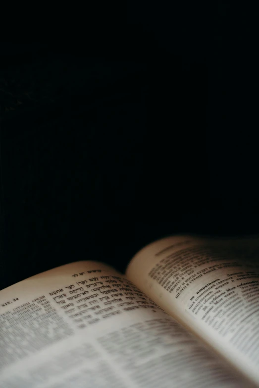 an open book sitting on top of a table, by Adam Chmielowski, underexposed, medium format. soft light, bible, black