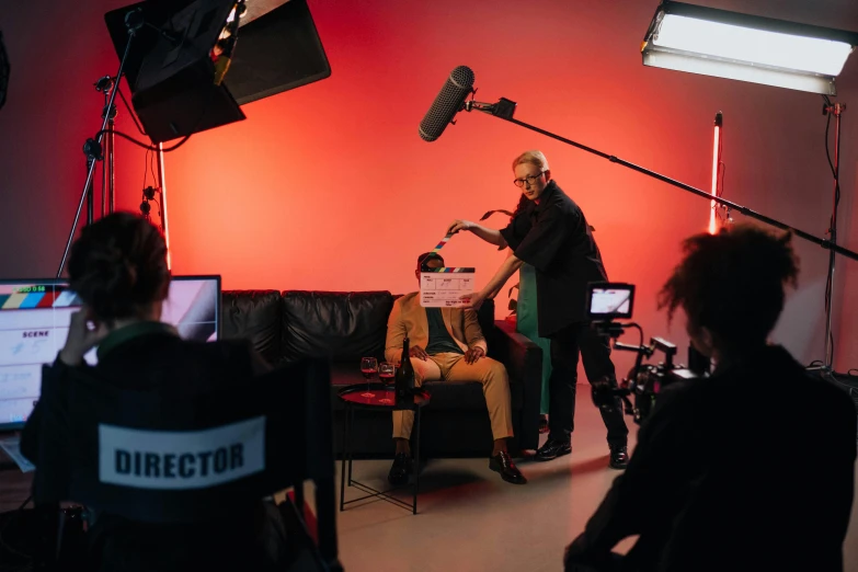 a woman sitting on a couch in front of a camera, pexels, video art, meet the actor behind the scenes, coloured gel studio light, person in foreground, official music video