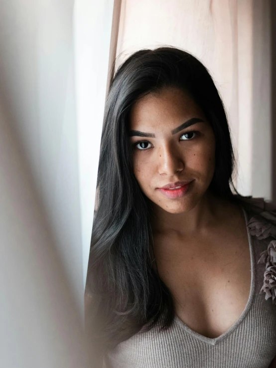 a beautiful young woman sitting in front of a window, a character portrait, by Andrée Ruellan, trending on unsplash, hurufiyya, gorgeous latina face, 🤤 girl portrait, taken in the late 2010s, looking straight into camera