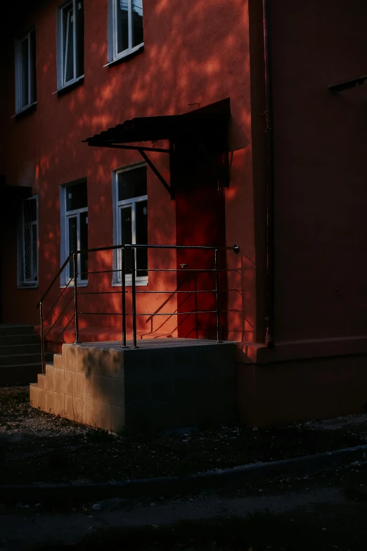 a man riding a skateboard up the side of a building, a picture, by Attila Meszlenyi, pexels contest winner, socialist realism, reddish exterior lighting, private academy entrance, contre jour, colors red