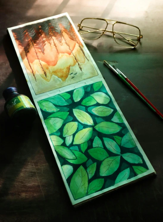 a bookmark sitting on top of a table next to a pair of glasses, a watercolor painting, inspired by Art Green, trending on polycount, green backlight leaves, experimental studio light, colored album art, on dark paper