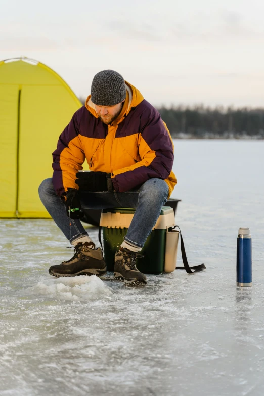 a man sitting in front of a yellow tent on a frozen lake, by Veikko Törmänen, trending on pexels, renaissance, fish in the background, drinking, ergonomic, multicoloured