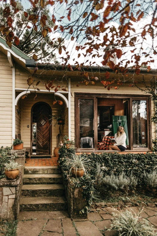 a person sitting on a porch in front of a house, pexels contest winner, arts and crafts movement, in australia, fall season, rustic setting, lush plant and magical details