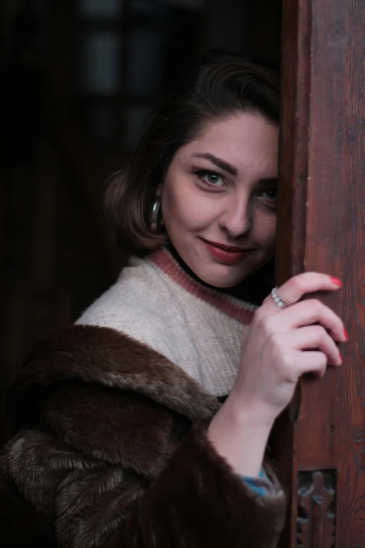 a woman in a fur coat leaning against a door, a portrait, inspired by Elsa Bleda, pexels contest winner, renaissance, dressed like in the 1940s, handsome girl, ((portrait)), stoya