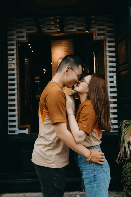 a man and woman kissing in front of a building, pexels contest winner, wearing a t-shirt, asian features, 🚿🗝📝, gif