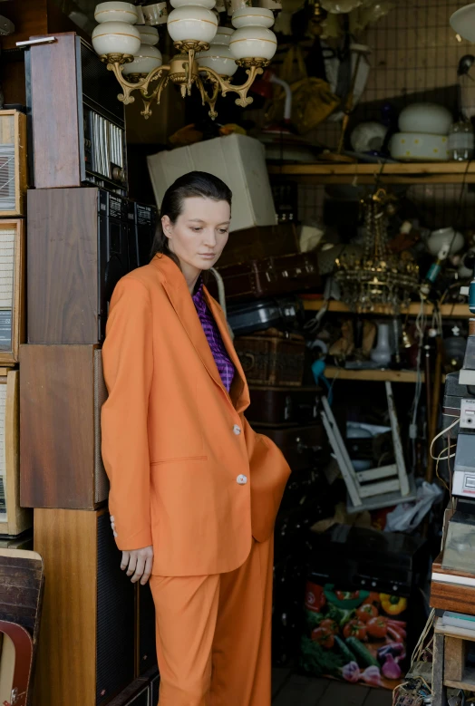 a woman in an orange suit standing in a shop, an album cover, unsplash, renaissance, old wool suit, office clothes, in style of juergen teller, wearing a worn out suit