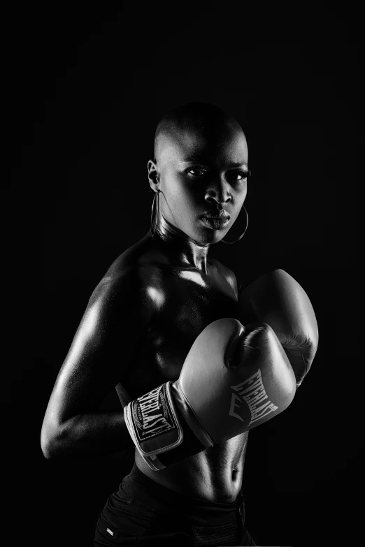 a black and white photo of a woman with boxing gloves, an album cover, pexels contest winner, a bald, ebony skin, sport, warrior woman