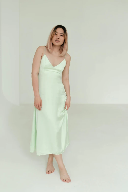 a woman standing in a white room wearing a green dress, reddit, wearing white silk, pale pastel colours, wearing a nightgown, uk
