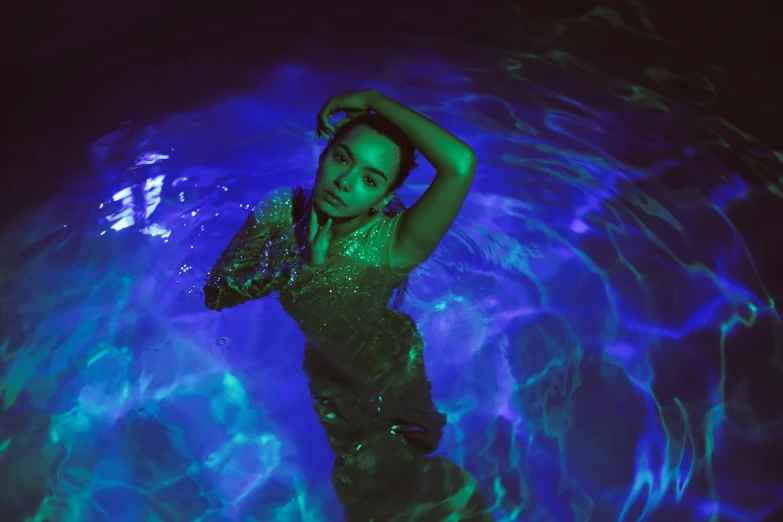 a woman in a green dress in a pool, an album cover, inspired by Elsa Bleda, pexels contest winner, holography, blue lights, jamie chung, purple glow, light skin