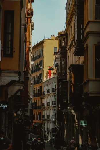 a city street filled with lots of tall buildings, a picture, by Cafer Bater, pexels contest winner, in spain, red black white golden colors, shady alleys, profile pic