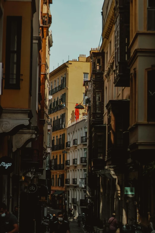 a city street filled with lots of tall buildings, a picture, by Cafer Bater, pexels contest winner, in spain, red black white golden colors, shady alleys, profile pic