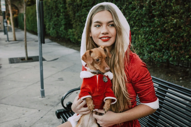 a woman sitting on a bench holding a small dog, pexels contest winner, renaissance, wearing festive clothing, wearing a scarlet hoodie, nina agdal, avatar image